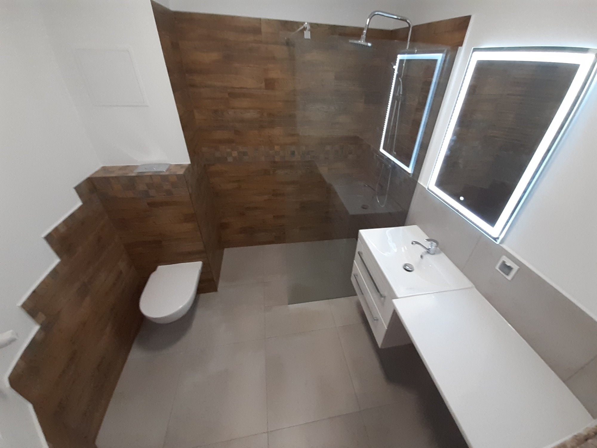 Nowoczesna łazienka z kabiną prysznicową typu walk-in, drewnopodobnymi płytkami na ścianach i podświetlanymi lustrami.