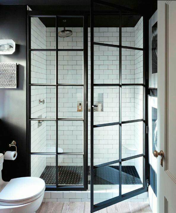 Nowoczesna kabina prysznicowa z czarnymi szprosami w Katowicach, widoczna przez otwarte drzwi, z toaletą w lewym dolnym rogu i czarno-białą kolorystyką wnętrza.