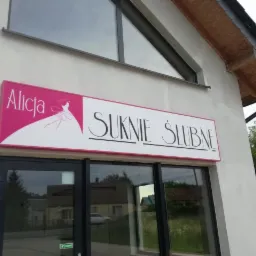 Szyld salonu sukien ślubnych 'Alicja Suknie Ślubne' nad wejściem do budynku z przeszklonymi drzwiami.