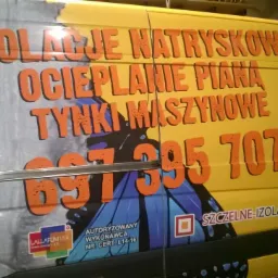 Żółty samochód dostawczy z reklamą natryskowej izolacji, ocieplania pianą i tynków maszynowych, z numerem telefonu i adresem strony internetowej.