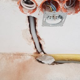 Remonty A.R.Z - Przygotowanie instalacji elektrycznej w ścianie: puszki instalacyjne, przewody w peszlu, uchwyt gniazdka, surowy tynk z ubytkami.