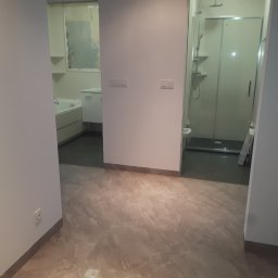 Remonty A.R.Z - Widok na dwie łazienki z korytarza, widoczna wanna, umywalka, kabina prysznicowa, płytki podłogowe imitujące marmur.