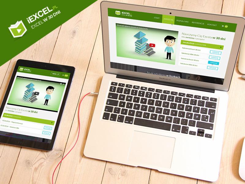 Laptop i tablet wyświetlające stronę internetową z kursem Excela, połączone czerwonym kablem audio na tle drewnianego biurka.