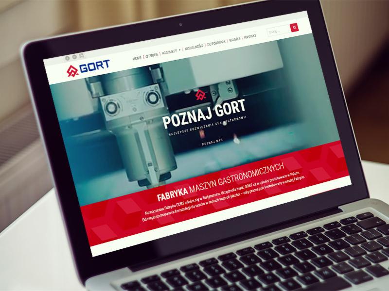 Laptop wyświetlający stronę internetową firmy GORT, prezentującą maszyny gastronomiczne, z widocznym logo i hasłem 'Poznaj GORT'.