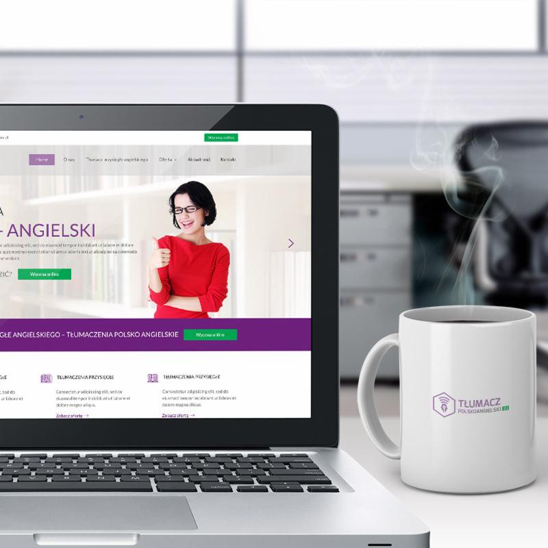 Laptop wyświetlający stronę internetową z tłumaczeniami polsko-angielskimi, obok biały kubek z logo firmy tłumaczeniowej, para unosząca się z kubka.