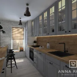 Wizualizacja szarej kuchni z drewnianym blatem, czarnym zlewem i trzema stołkami barowymi, oświetlona lampami wiszącymi w stylu industrialnym, z logo projektanta w prawym dolnym rogu.