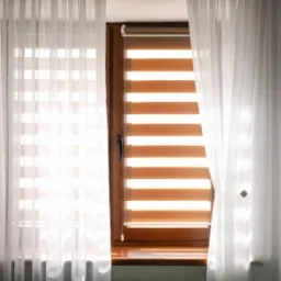 Okno z drewnianą ramą, przesłonięte białymi, prześwitującymi zasłonami i roletą w poziome pasy w odcieniach bieli i beżu, częściowo opuszczoną.