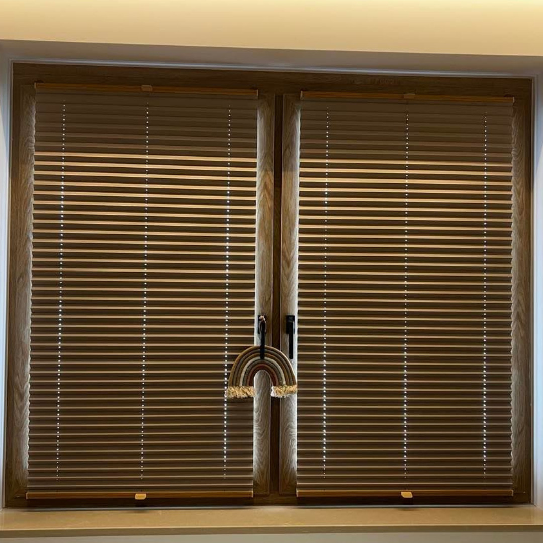 Drewniane okno z brązowymi żaluzjami poziomymi, ozdobione makramowym tęczowym wisiorkiem.