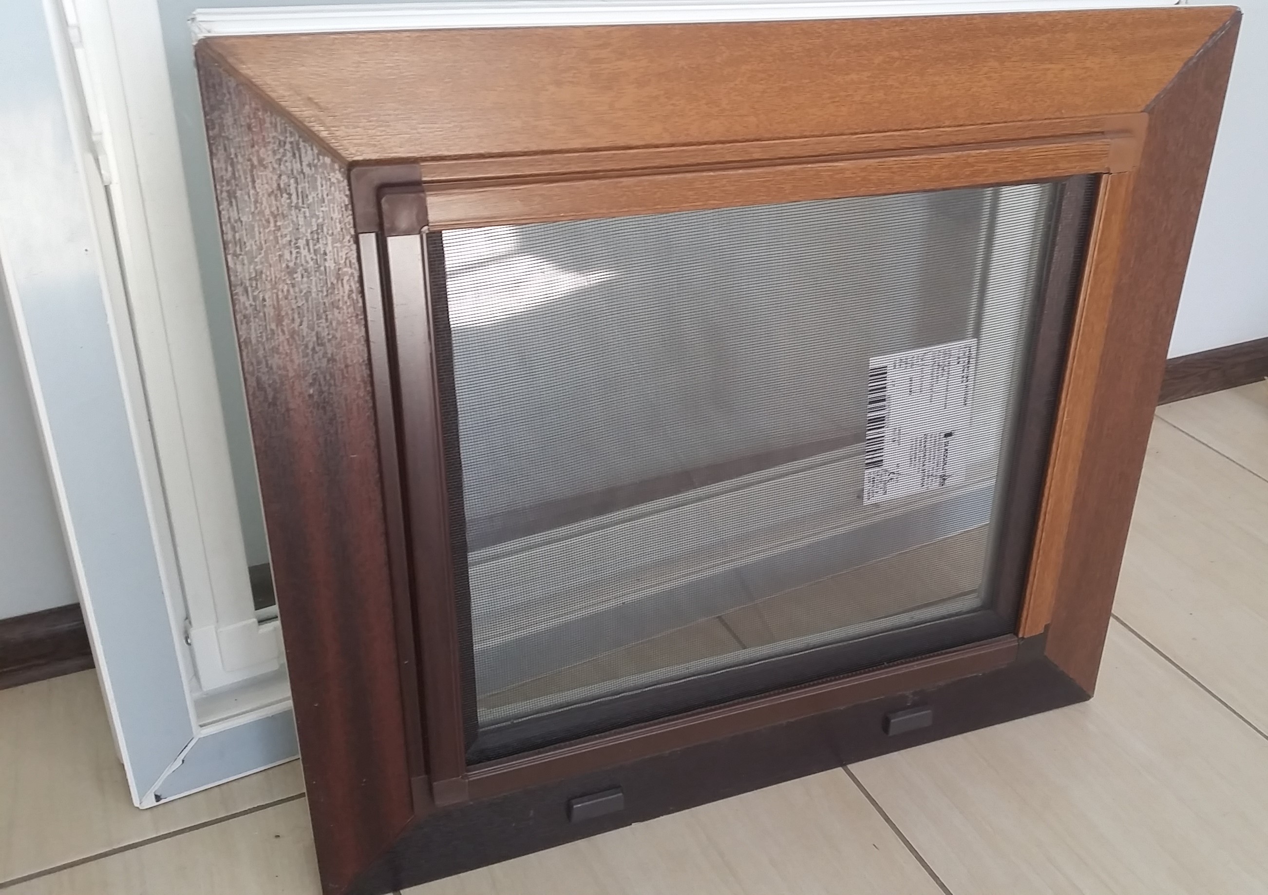 Drewniana rama okienna z plisą w Łowiczu, widoczna etykieta z kodem kreskowym na plisie.