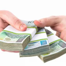 Dłonie mężczyzny w koszuli w paski trzymające trzy pliki spiętych banknotów polskich złotych (100 i 50 zł) na białym tle.