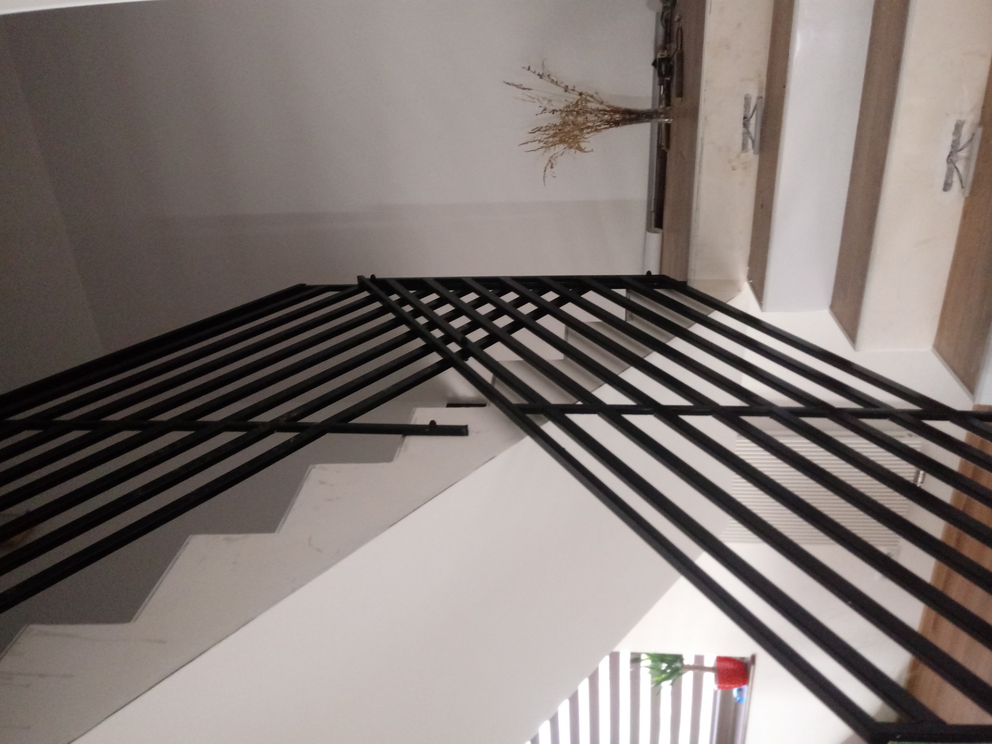 Nowoczesna, czarna balustrada schodowa z metalowych prętów, widok z dołu, minimalistyczny design.