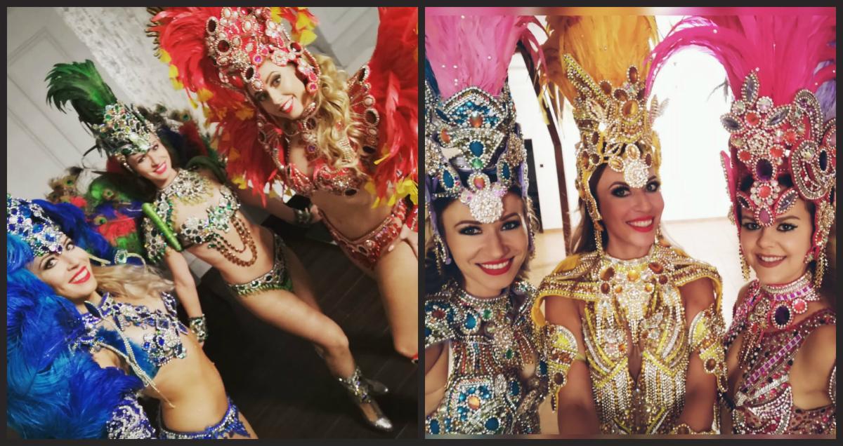 Dwie grupy kobiet w bogato zdobionych, kolorowych strojach karnawałowych z piórami i cekinami, uśmiechnięte i pozujące do zdjęcia.
