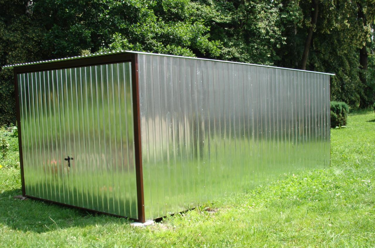 Gotowy garaż blaszany z brązowymi obramowaniami, umieszczony na trawniku w ogrodzie.