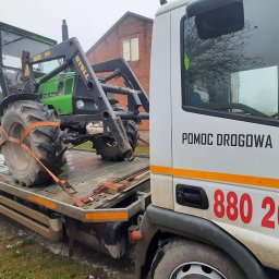 LAWETA Pomoc Drogowa TUCHÓW Transport HOLOWANIE - Zielony traktor Deutz-Fahr DX 4.51 z ładowaczem czołowym Stoll, zabezpieczony pomarańczowymi pasami transportowymi na niskopodwoziowej platformie lawety z napisem 'POMOC DROGOWA' i numerem telefonu...