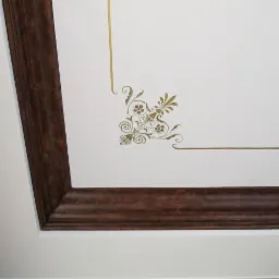 Fragment sufitu z dekoracyjnym, ciemnym obramowaniem i złoconym ornamentem roślinnym w rogu.