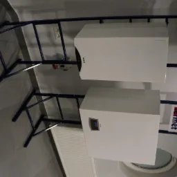 Dwa białe kotły gazowe marki Termet zamontowane na niebieskim stelażu, widoczne elementy instalacji, grzejnik panelowy i fragment toalety w tle.