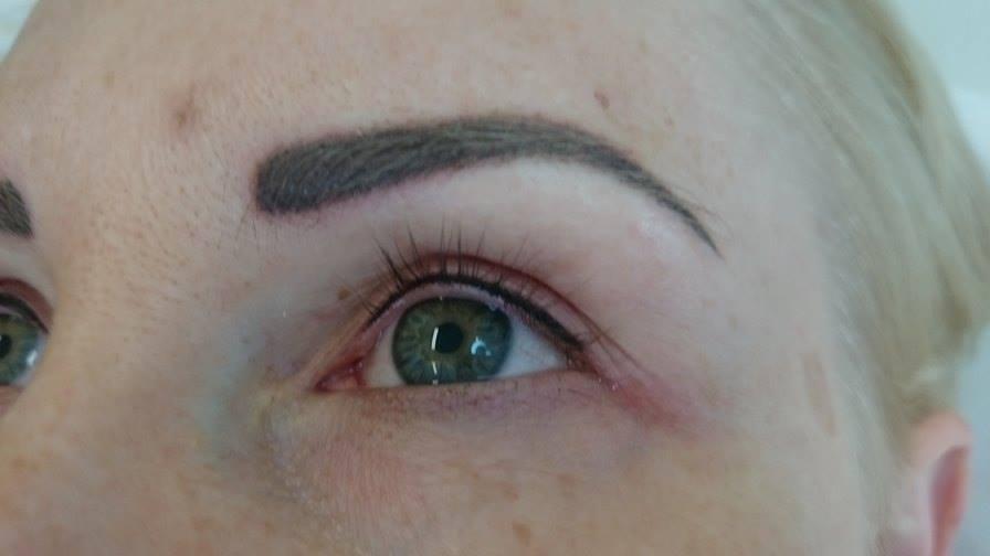 Zbliżenie na oko z precyzyjnie wykonanym permanentnym makijażem brwi i kreską na powiece, widoczne pojedyncze rzęsy i zielona tęczówka.