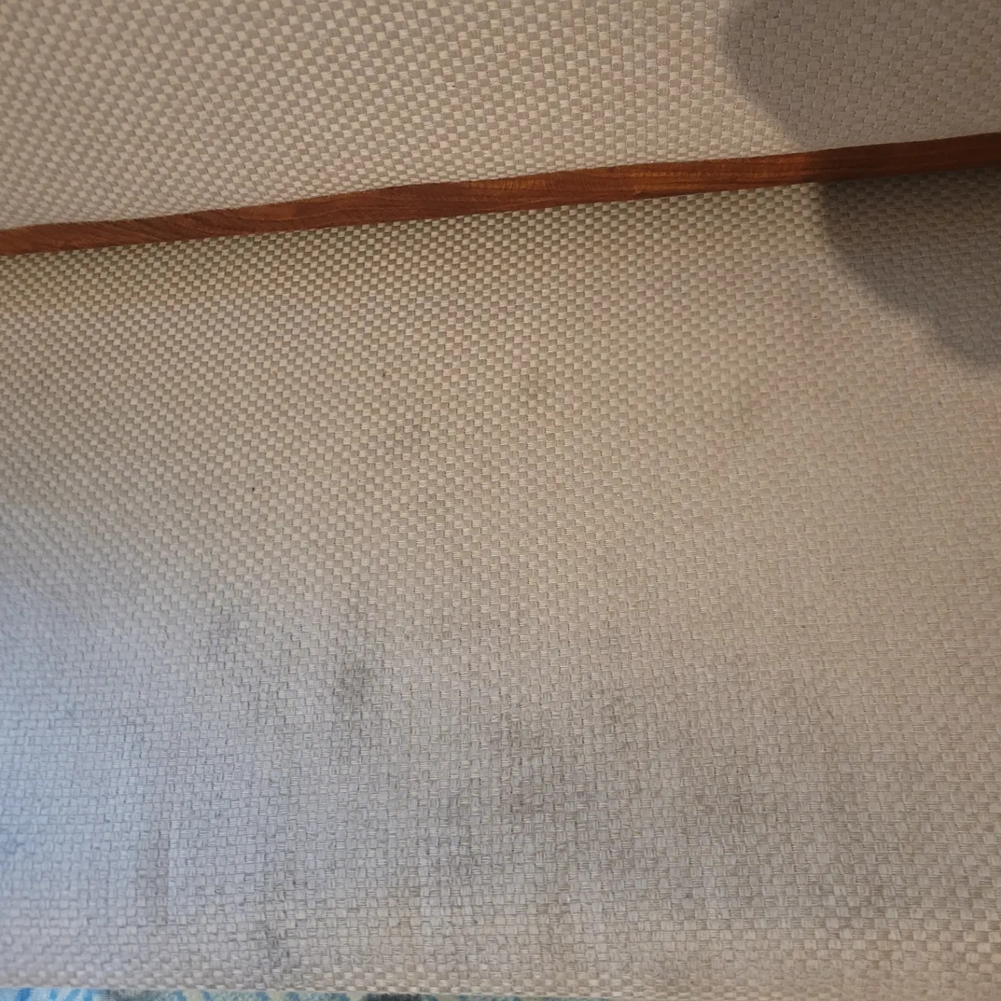 Szczegółowe ujęcie tekstylnej rolety okiennej z drewnianą listwą w Książu Wielkim, ukazujące plamy i zabrudzenia na jasnej, tkanej powierzchni.