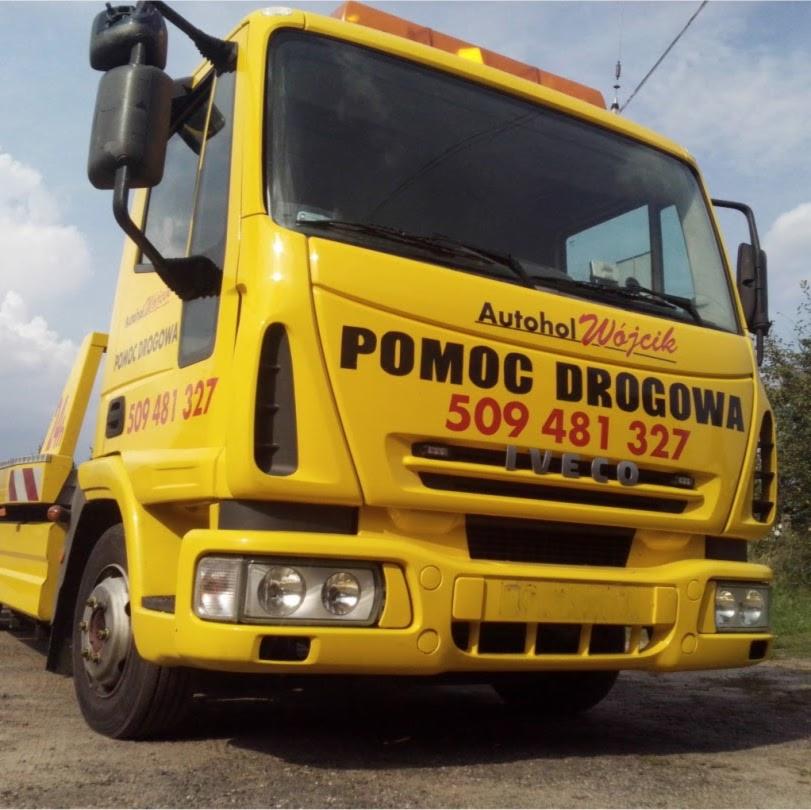 Żółty pojazd pomocy drogowej marki Iveco z napisem 'Pomoc Drogowa' i numerem telefonu, stojący na poboczu drogi.