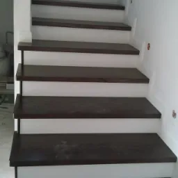 Nowoczesne schody z ciemnego drewna i białymi podstopnicami, widok z dołu, oświetlenie dzienne.