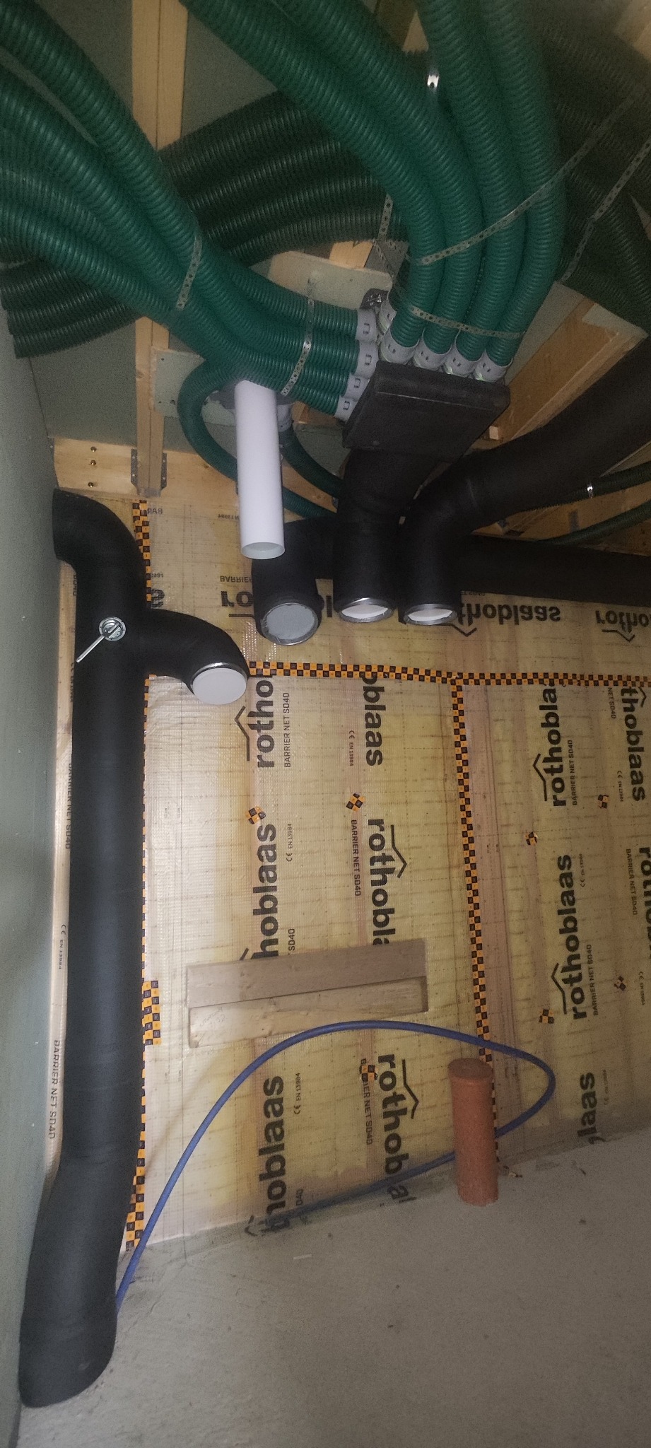 Zielone i czarne rury wentylacyjne zamontowane pod stropem, widoczne elementy instalacji rekuperacji w trakcie montażu.