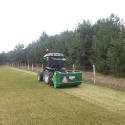 Grass&Water - Zielony traktor Peruzzo z kosiarką rotacyjną na łące, świeżo skoszony pas trawy, widok z tyłu, drzewa w tle, ogrodzenie z siatki.