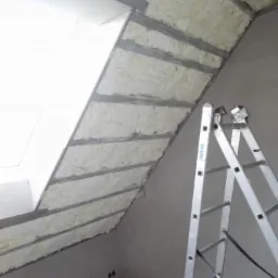 Poddasze z ociepleniem pianką PUR pomiędzy metalowymi profilami, widoczna drabina Krause, surowy stan wykończenia ścian.