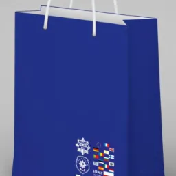 Granatowa torba papierowa z białymi uchwytami, nadrukowanym logo policyjnym EUPST II i flagami państw członkowskich UE.
