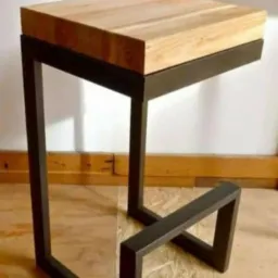 Nowoczesny taboret barowy z blatem z jasnego drewna i metalową ramą w kolorze antracytu, o geometrycznej konstrukcji podstawy