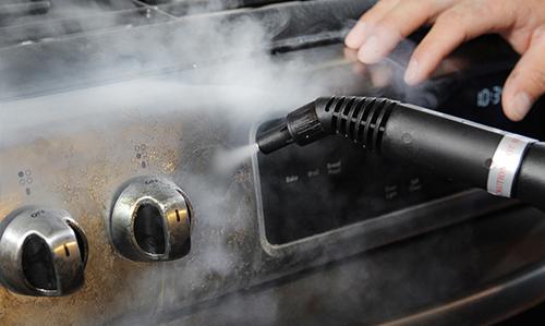 Czyszczenie piekarnika parą za pomocą parownicy ręcznej, widoczne pokrętła i wyświetlacz czasu.