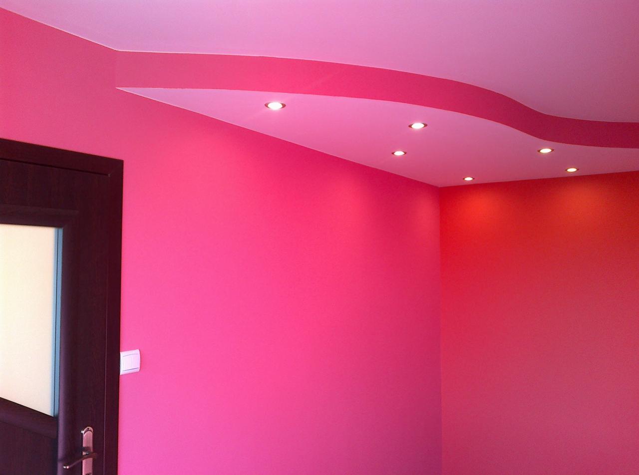 Pokój po malowaniu w odcieniach różu i czerwieni, z dekoracyjnym podwieszanym sufitem i wbudowanymi punktowymi lampami, widoczna część drzwi.