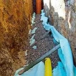 Krys - Wykop z ułożoną rurą drenarską, obsypany żwirem i zabezpieczony geowłókniną, widok z góry.