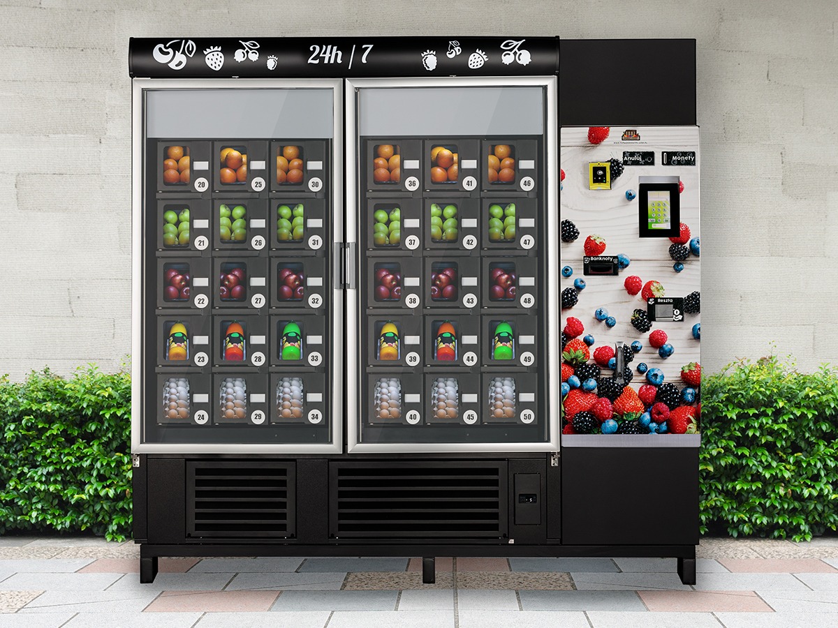 Automat vendingowy z owocami i jajkami, oferujący dostęp 24h/7, z ilustracją różnorodnych owoców na bocznej ściance.