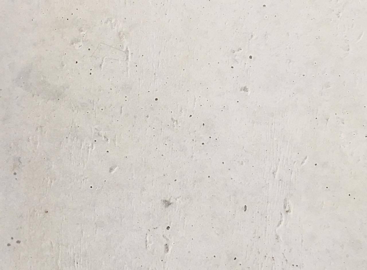 Jasnoszara, gładka powierzchnia z betonu architektonicznego z drobnymi porami i śladami po szalunku.