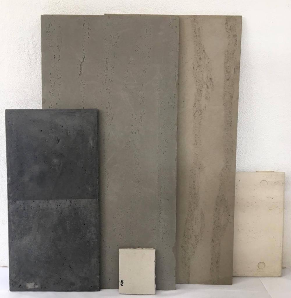 Zestaw próbek płyt z betonu architektonicznego w różnych odcieniach szarości i beżu, prezentujących różnorodne faktury i wykończenia powierzchni.