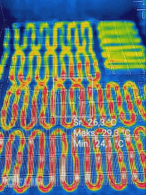 Termowizyjne zdjęcie ogrzewania podłogowego, widoczne rury grzewcze w kolorach od niebieskiego (zimny) do żółtego (ciepły), z zaznaczonymi temperaturami minimalną, średnią i maksymalną.