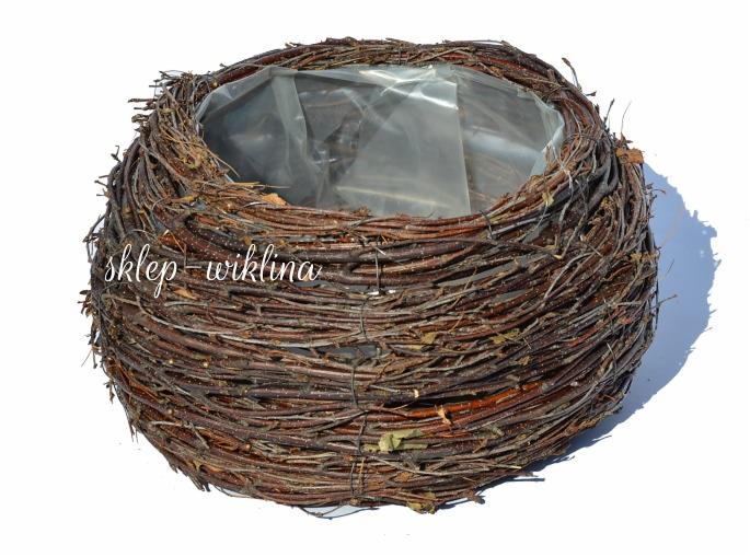 Okrągła donica z gałęzi brzozy, wyłożona przezroczystą folią, widoczna w całości na białym tle w jasnym oświetleniu.