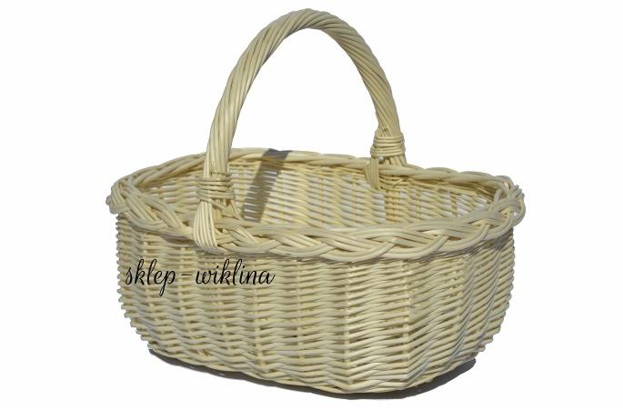 Owalny, pleciony z jasnej wikliny kosz z uchwytem, widoczny na białym tle.