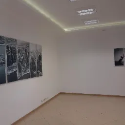 Pomalowane na biało wnętrze biura z panelami przedstawiającymi panoramę miasta w czerni i bieli, oraz jasną podłogą z płytek.