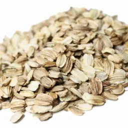 Kępa płatków owsianych na białym tle, z widocznymi charakterystycznymi bruzdami i jasnobrązową kolorystyką.