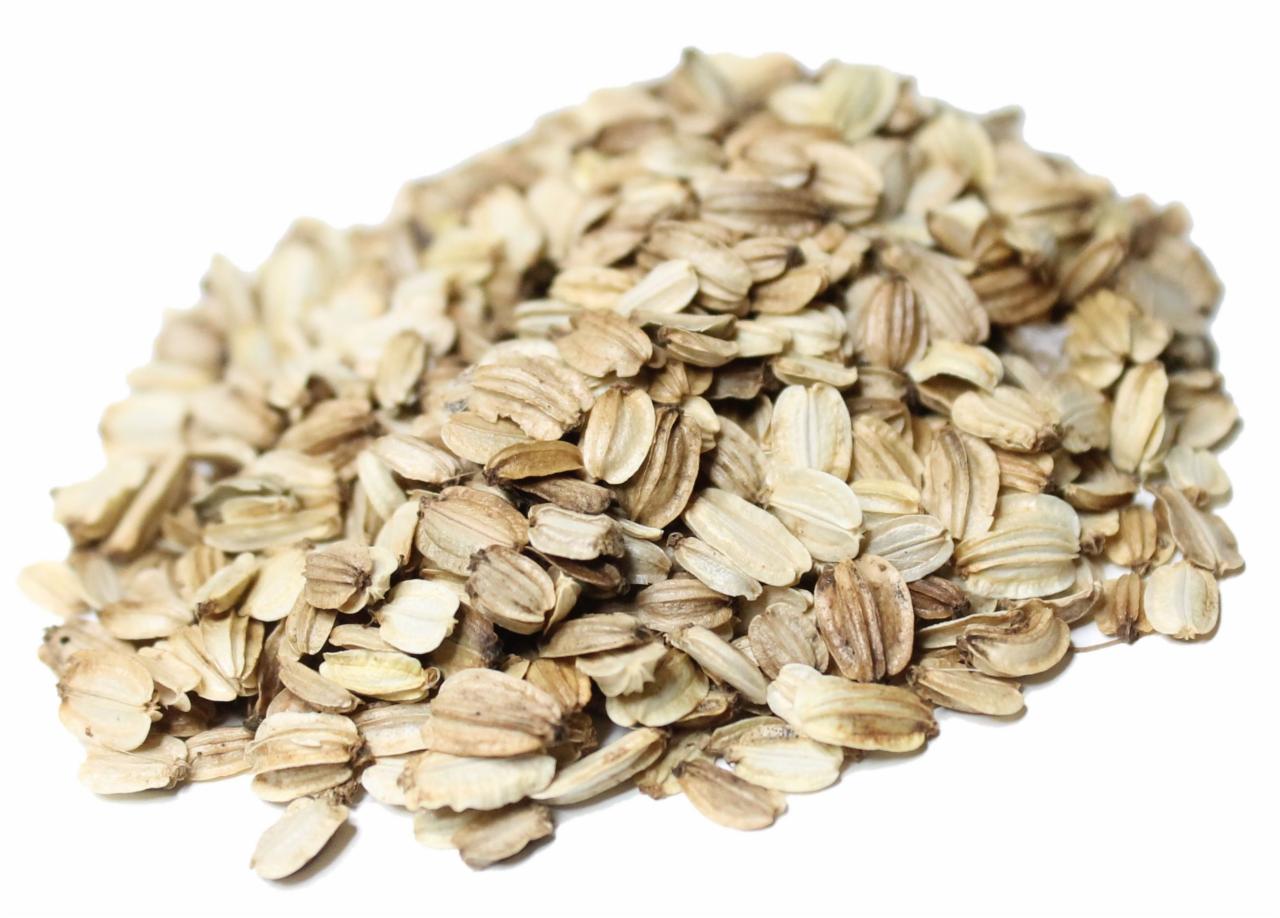 Kępa płatków owsianych na białym tle, z widocznymi charakterystycznymi bruzdami i jasnobrązową kolorystyką.