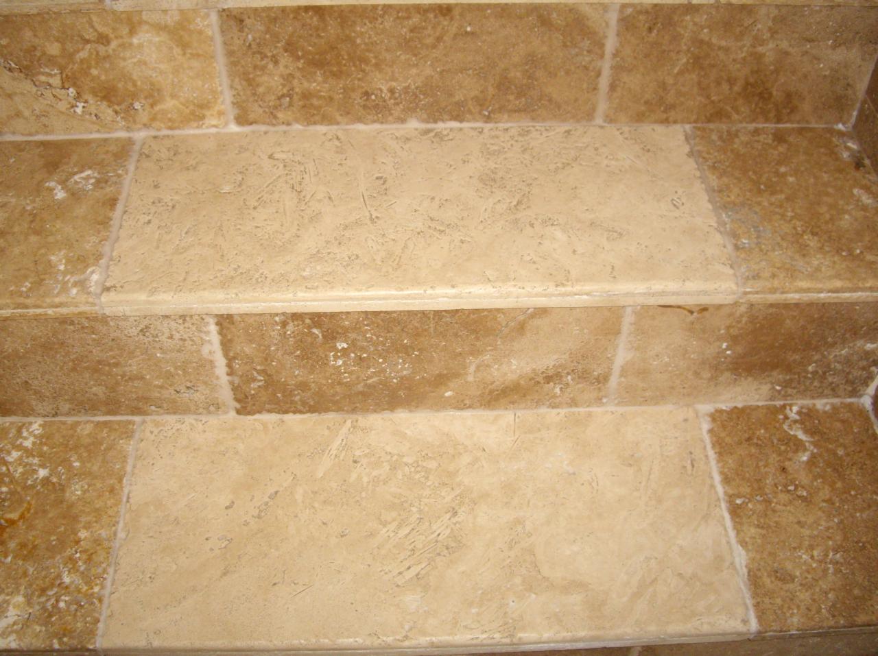 Wykończone schody wewnętrzne wyłożone beżowymi płytkami imitującymi trawertyn, z widocznymi naturalnymi porami i żyłkami kamienia.