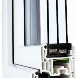 Przekrój poprzeczny ramy okiennej z tworzywa sztucznego, prezentujący wielokomorową konstrukcję i system uszczelnień, widoczne cztery szyby zespolone.