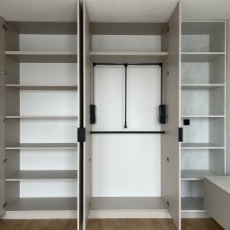 FHU JACK - Otwarta, beżowa szafa wnękowa z półkami i drążkiem na ubrania, wykończona marmurowym wzorem na tylnej ścianie, na tle drewnianej podłogi.