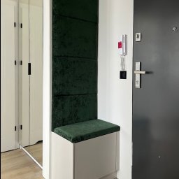 FHU JACK - Nowoczesna zabudowa przedpokoju: biała szafka z siedziskiem obitym butelkową zielenią, panele ścienne w tym samym kolorze. Obok drzwi wejściowe i lustrzana szafa.