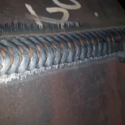 Szczegółowe zbliżenie na estetyczne spawy na metalowej rurze, ukazujące precyzyjne łączenia i strukturę materiału.