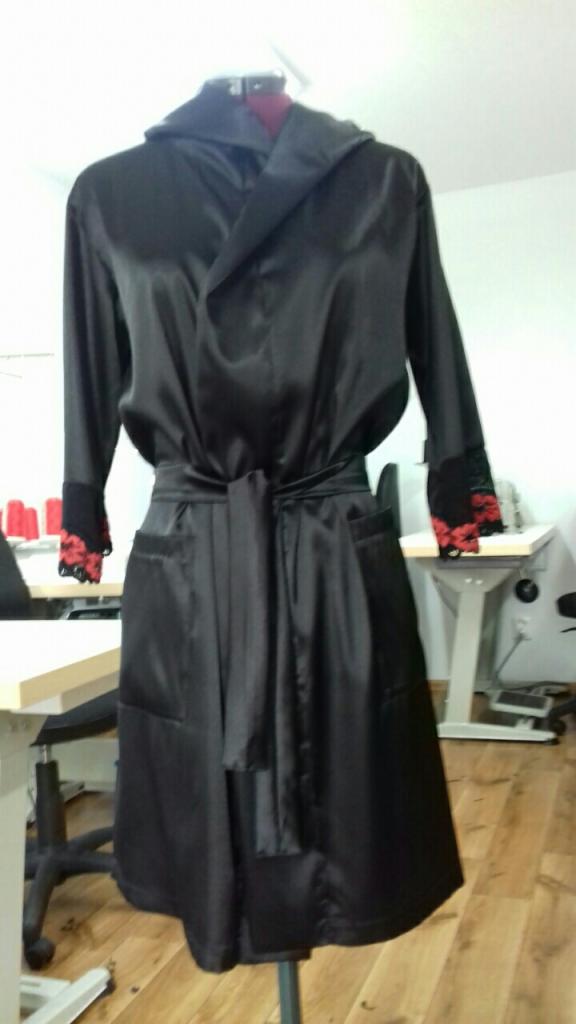 Czarny, satynowy szlafrok z czerwonymi koronkowymi mankietami, prezentowany na manekinie w pracowni w Krakowie.