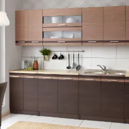 Nowoczesna kuchnia z dwukolorowymi frontami: górne szafki w odcieniu jasnego drewna z przeszklonymi witrynami, dolne w tonacji ciemnego brązu, uzupełniona beżowym blatem i białymi płytkami.