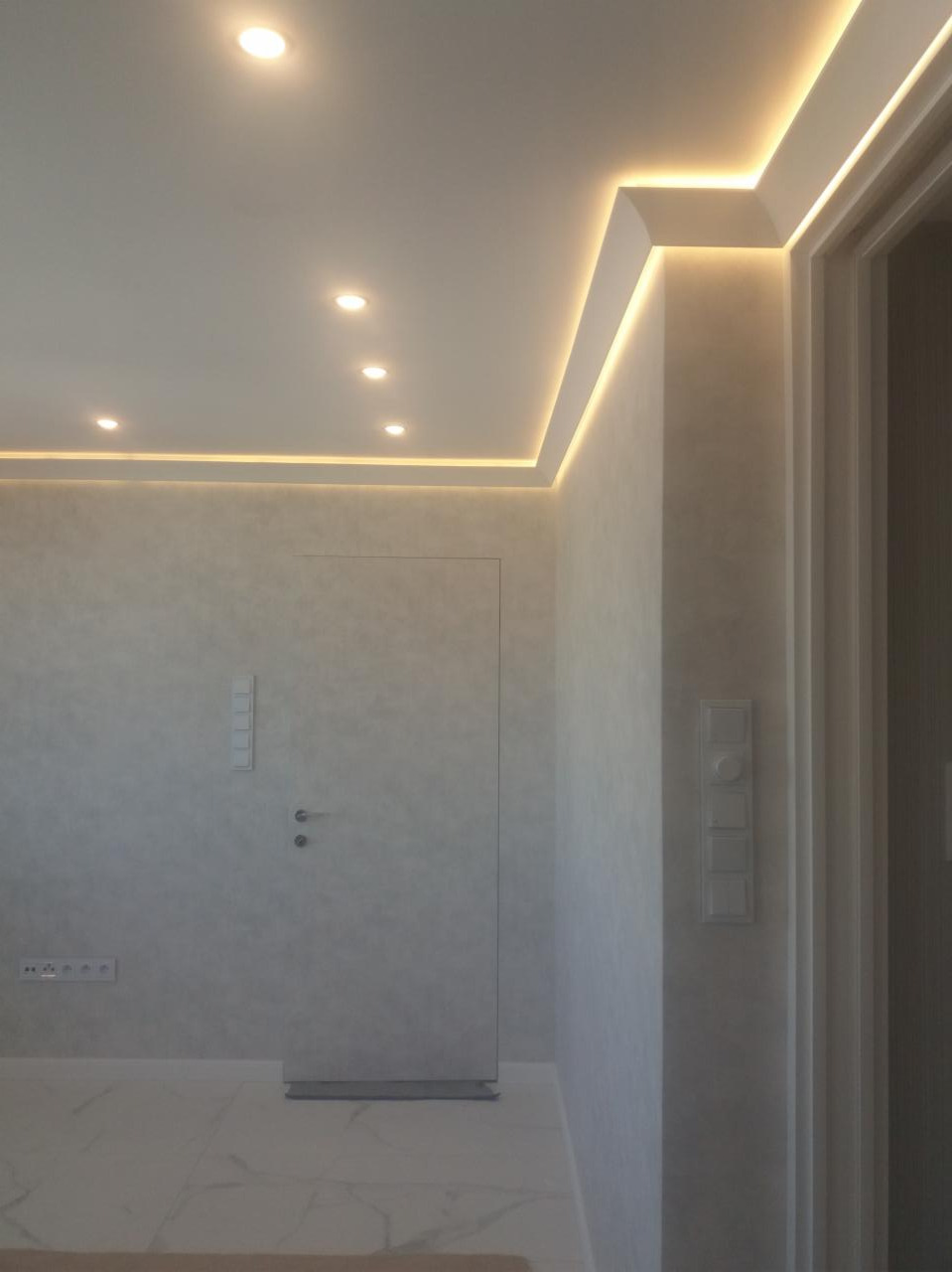 Minimalistyczne wnętrze z ukrytymi drzwiami, oświetleniem LED na suficie i marmurową podłogą