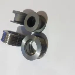 Trzy metalowe tuleje z rowkami i kołnierzami, ułożone na białym tle, ukazujące precyzyjną obróbkę i detale powierzchni.